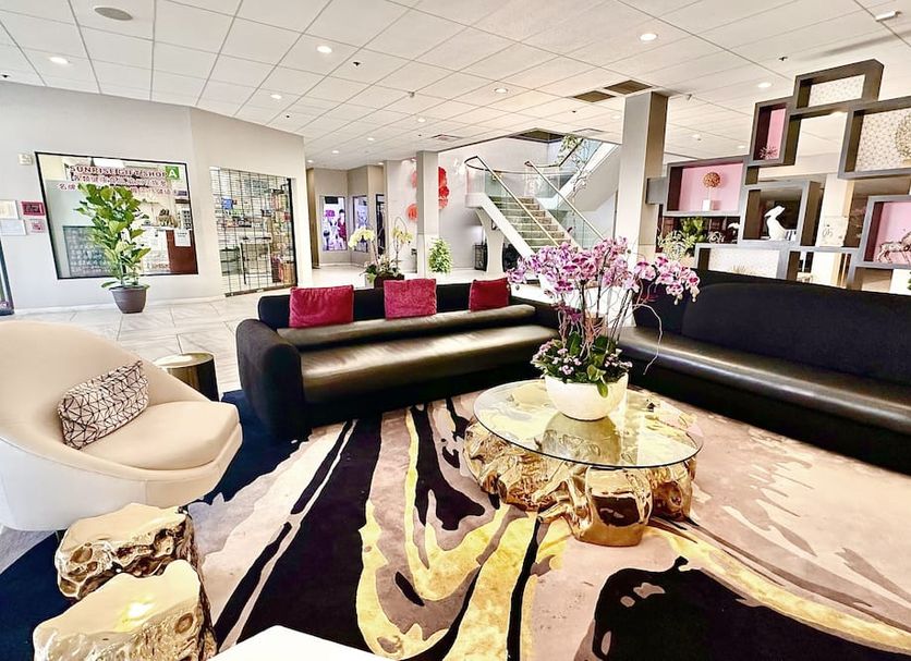 Lincoln Hotel Monterey Park Los Angeles lobby with black sofas, gold coffee table and floral arrangement