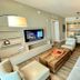 Lyfe Resort And Residences Hollywood living room with sofa, armchairs, TV and kitchen area