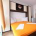 Apartments Alissa in Hvar bedroom with orange bedspread, wall-mounted storage, and kitchen doorway