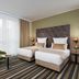 Leonardo Hotel Offenbach Frankfurt room with two twin beds, green chairs, and floor-to-ceiling window in Offenbach am Main