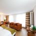 Hotel Alfa in Birsfelden guest room with two beds, armchairs, desk and large window