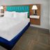 Hampton Inn Kansas City The Legends guest room with king bed and wall-mounted lamps in Kansas City