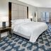 Sheraton Eatontown Hotel guest room with king bed, seating area, and patterned blue carpet in Eatontown
