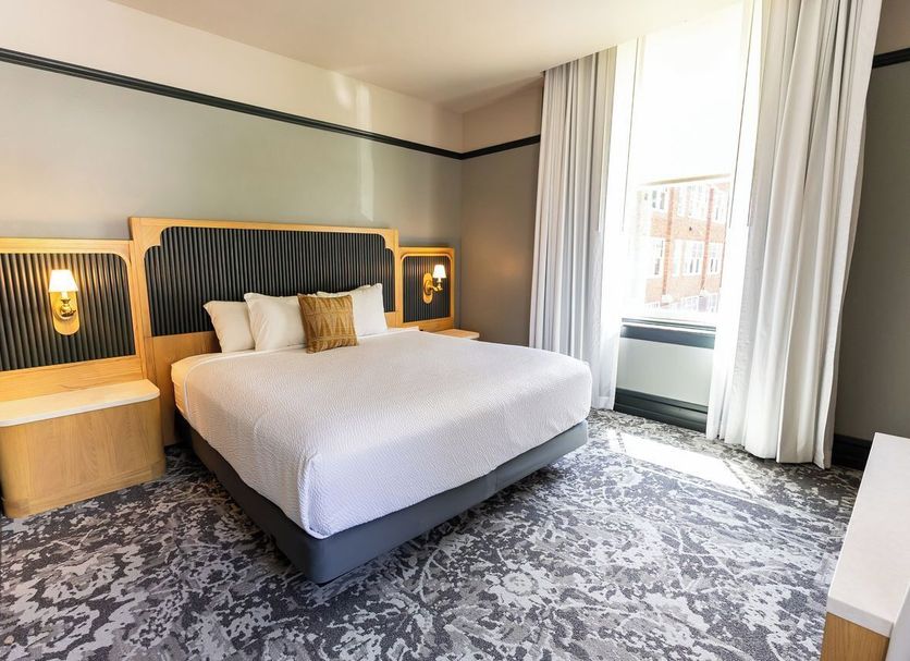Historic Franklin Hotel Deadwood guest room with king bed, patterned carpet, and tall windows
