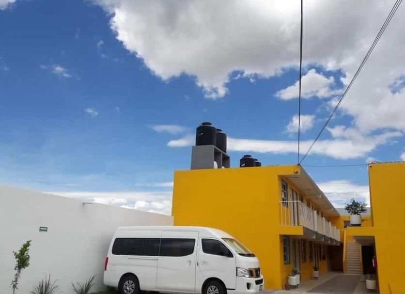 Posada del Ángel in Pachuca with yellow exterior, white van, and blue sky