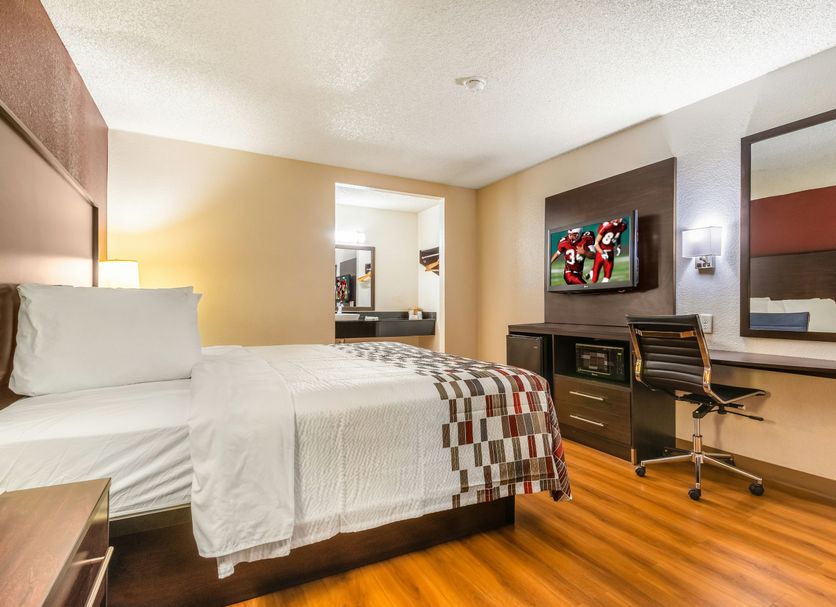 Red Roof Inn Phoenix-Midtown room with bed, desk, wall-mounted TV, and chair in Phoenix