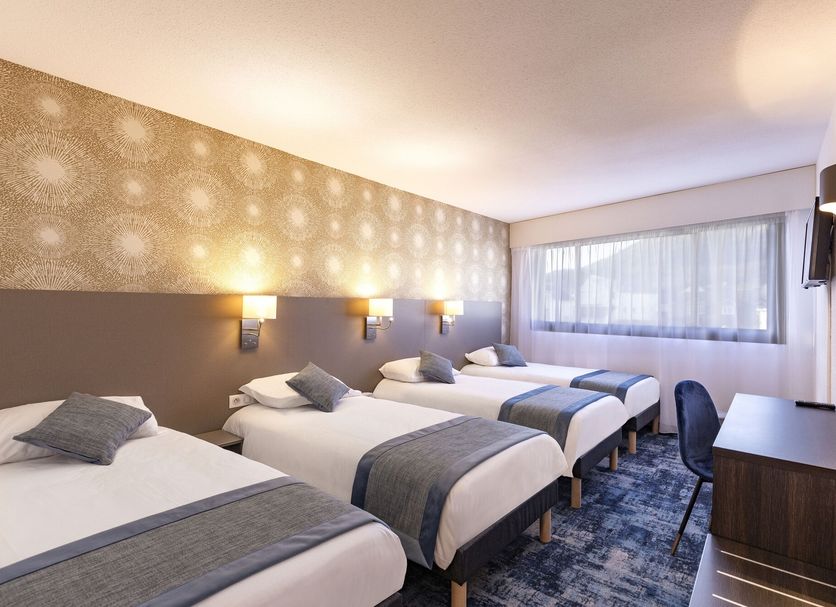 Hotel National Lourdes triple room with three single beds, desk, wall lights and window view