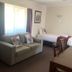 Armidale Pines Motel room in Armidale with sofa, single beds, and window curtains