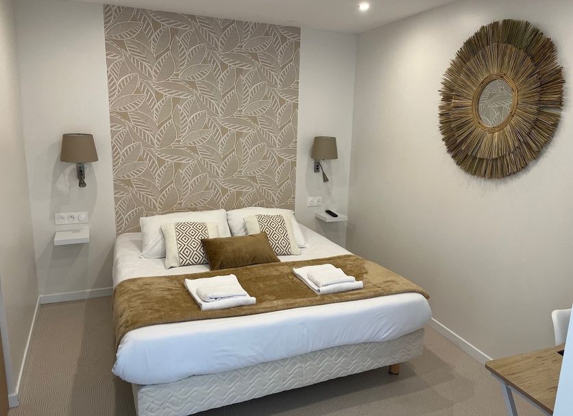 Hôtel Le Saint Patrice Bayeux guest room with double bed, patterned headboard wall and decorative mirror