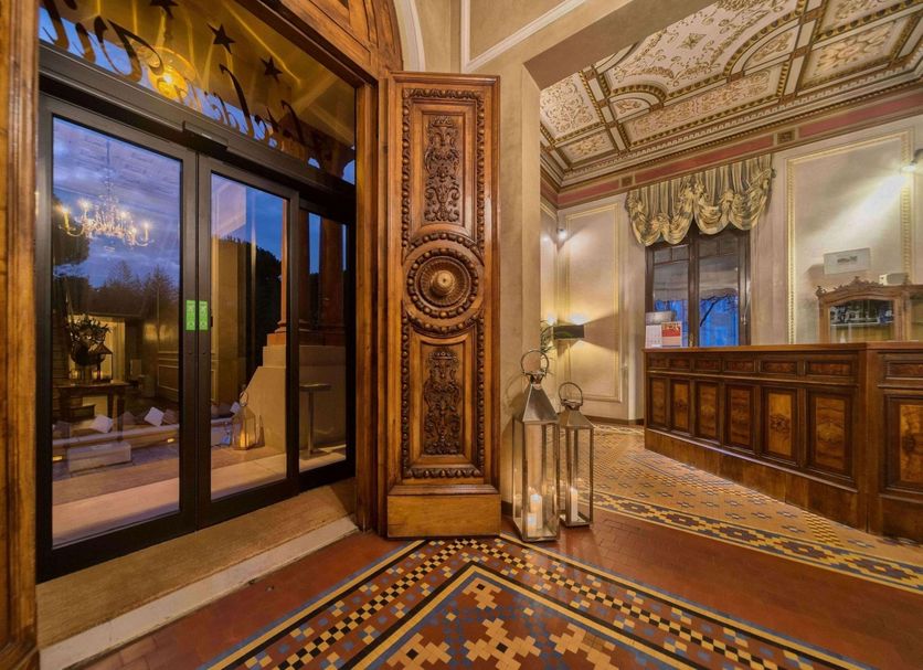 Hotel De la Ville in Riccione lobby with ornate carved wood, mosaic floor, and glass doors