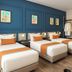 Kuala Lumpur International Hotel room with three twin beds, blue accent wall, and wood flooring in Kuala Lumpur