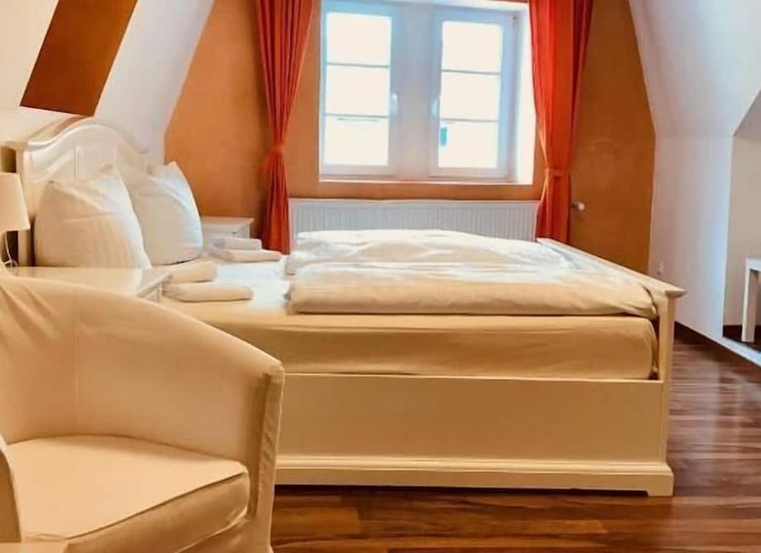 Hotel am Markt in Saarburg guest room with double bed, window, and upholstered chair