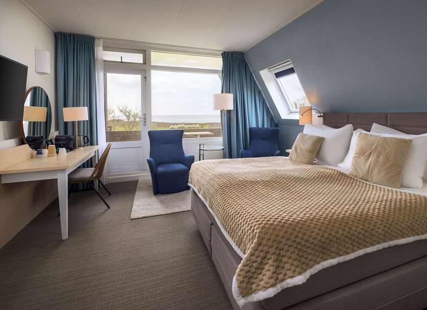 WestCord Hotel de Wadden room in Oost-Vlieland with sea view, bed, desk and blue chairs