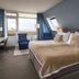 WestCord Hotel de Wadden room in Oost-Vlieland with sea view, bed, desk and blue chairs