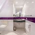 Premier Inn Stuttgart Airport bathroom with accessible shower chair, sink and purple tiled accent wall