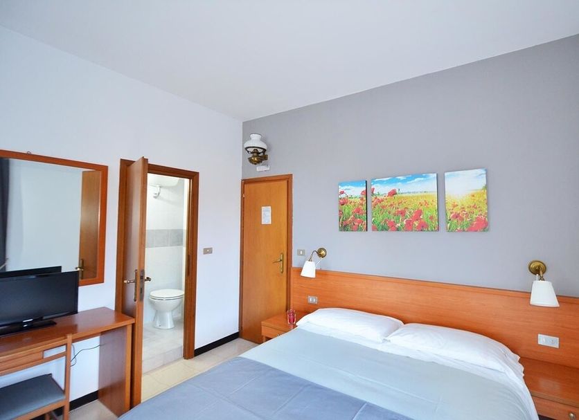 Porta del Parco in Camogli: simple guest room with double bed, desk, TV and en suite bathroom door