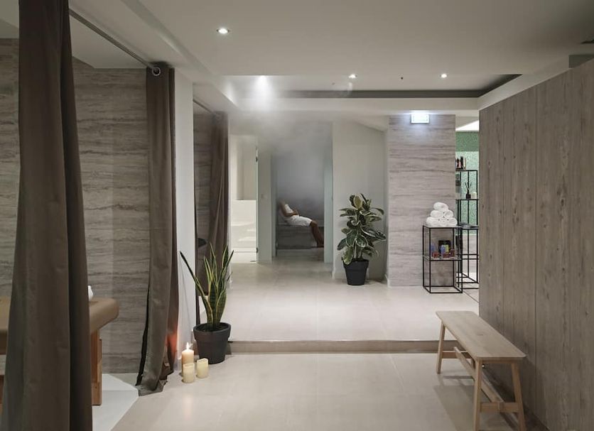 The Gem Society Hotel Athens lobby with minimalist seating, potted plant, and soft ambient lighting