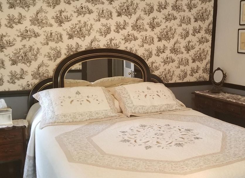 Lost Bayou Guesthouse in Galveston bedroom with ornate bed, floral wallpaper and vintage decor