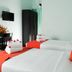 Blooming Paradise Thekkady room with twin beds, orange pillows, towels, wardrobe and wall-mounted TV