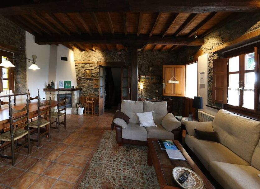 Casa de Aldea La Pumariega in Oviedo: rustic lounge with sofas, dining table, stone walls and wood beams