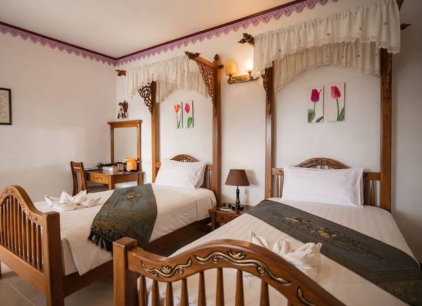 Ban Ao Thong in Trang: twin beds in a simple hotel room with carved wooden frames and wall art