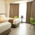 Swiss-Belhotel Borneo Samarinda twin room with two beds, green chair and floor-to-ceiling curtains in Samarinda