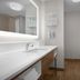 Hampton Inn Yorkville bathroom with long vanity, wall mirror, shower curtain and wood-look flooring