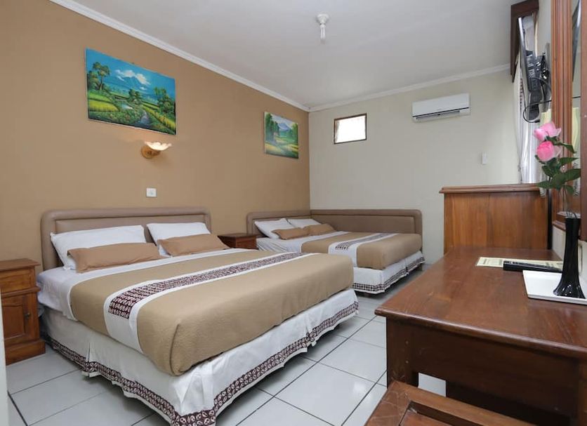 Hotel Mataram Malioboro Yogyakarta room with two beds, desk, wall art and air conditioner