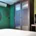 High Point Surabaya guest room with wardrobe, TV, and green patterned walls