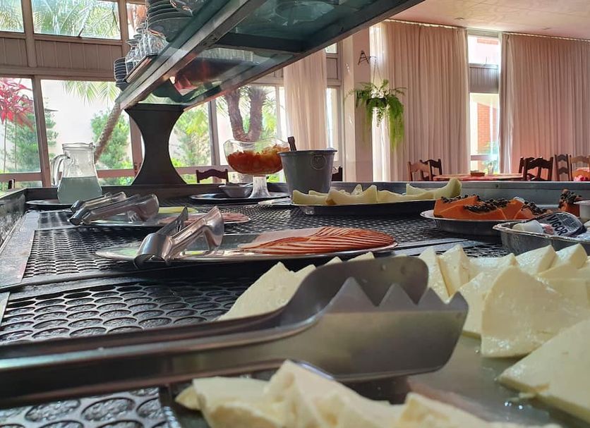 Ancona Center Hotel in Amparo buffet with tongs, sliced cheese and salmon on a counter by windows