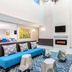 La Quinta Inn & Suites by Wyndham Hillsboro lobby with blue seating, geometric stools, and a wall-mounted fireplace