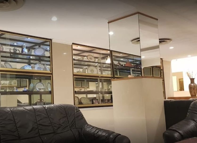 Hotel El Biar in Algiers lobby lounge with black chairs and glass shelving displaying dishes