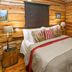 Riverside Guest Lodge in Oudtshoorn guest room with log walls, king bed, bedside lamps and wood accents