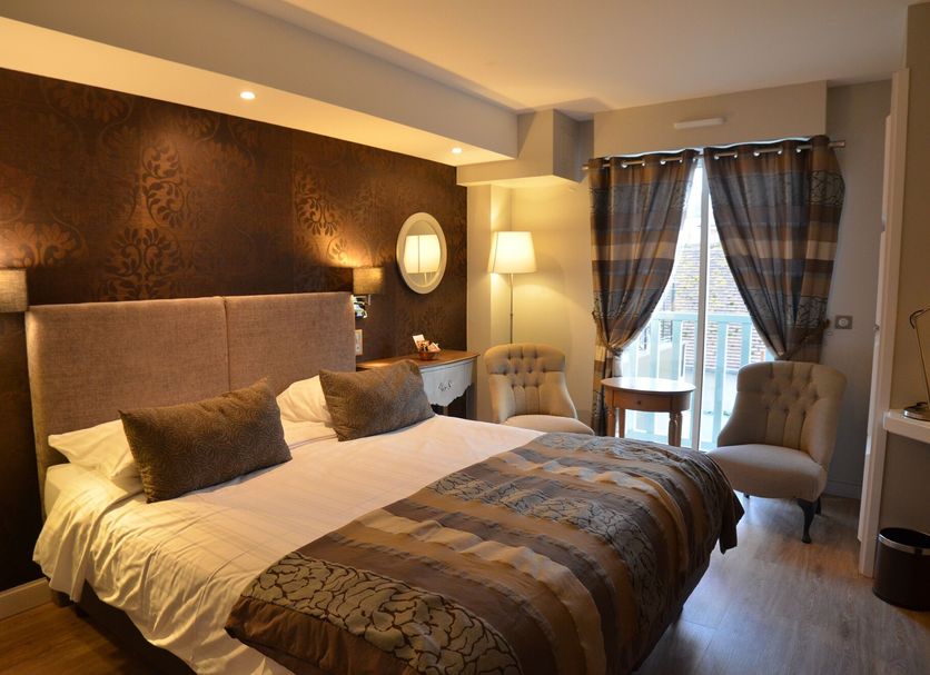 Villa Augeval Hôtel de charme & Spa in Deauville guest room with king bed, chairs and balcony doors