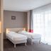 Appart'City La Rochelle room with two single beds, kitchenette, and large window with sheer curtains