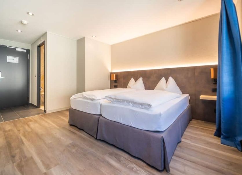 The Guesthouse by The Hey Hotel in Interlaken, twin beds in a modern guest room with wood flooring