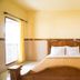 Tanjung Alam Hotel in Buleleng guest room with wooden bed, window, and wall-mounted air conditioner