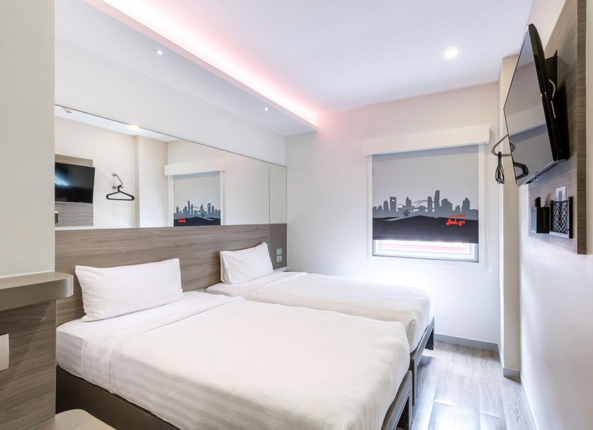 Easy Planet Bangkok Surawong room with two twin beds, wall-mounted TV, and Bangkok skyline art in Bangkok