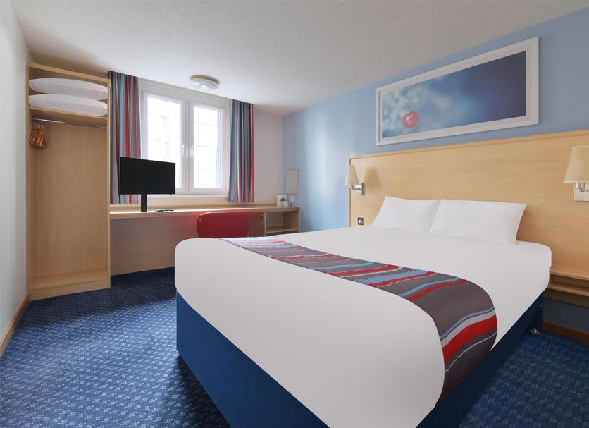 Travelodge Manchester Birch M62 Eastbound bedroom in Heywood with double bed, desk, window and blue carpet
