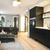 Home Again Apartments Nygata 1 in Stavanger: modern apartment living area with black sofa, kitchenette, and dining space.