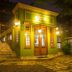 Pousada Perequê in Ilhabela, a brightly lit green facade with patterned tile stairs at night