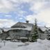 Glacier Lodge in Whistler with snow-covered chalet buildings and trees under a cloudy winter sky