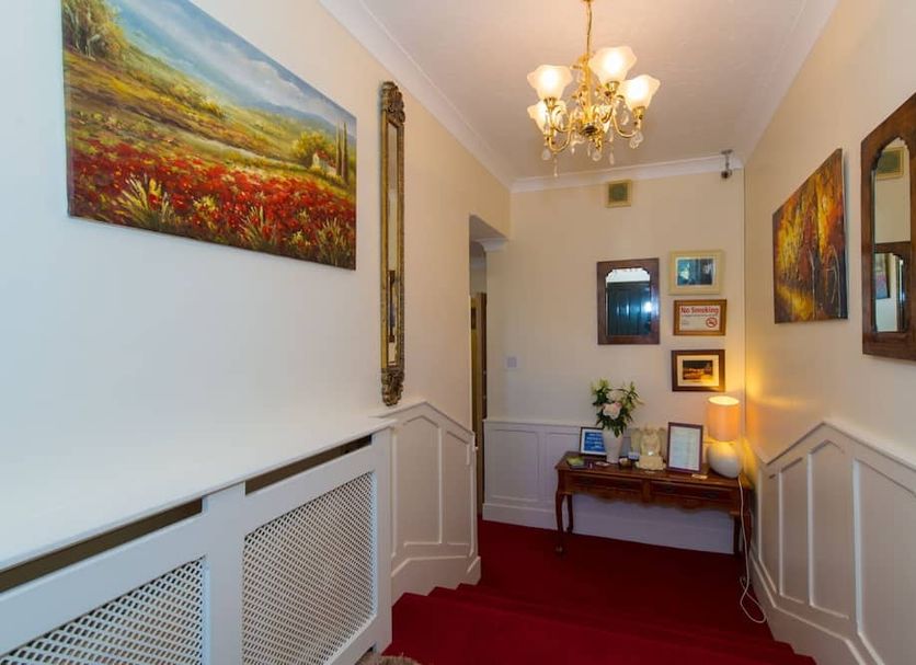 Aisleigh Guest House in Leitrim hallway with red carpet, chandelier, wall art and a small console table