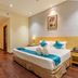 The Platinum Hotel in Hyderabad guest room with king bed, teal chairs, and small seating area