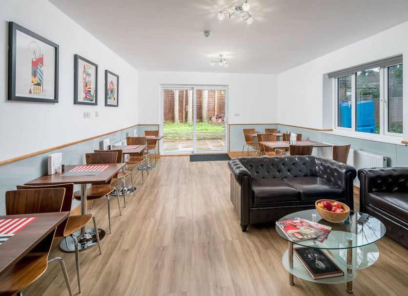 Flexistay Aparthotel Sutton lounge with tables, black sofas, glass coffee table and garden access