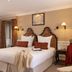 Ermitage - Mont-Saint-Michel guest room with twin beds, wall sconces, and seating area in Beauvoir