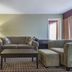 Quality Inn & Suites Windsor guest lounge with sofa, chairs, coffee table, lamp and window
