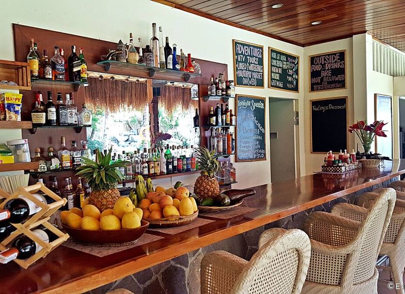 Mike's Dauin Dive Resort bar with fruit display, liquor shelves, and wicker bar stools in Dauin