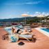 Kythea Resort in Agia Pelagia: poolside sun loungers beside a blue outdoor pool with sea and hillside views