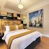 Casa Panuco in Mexico City bedroom with queen bed, mustard accents, wood floors, and coastal wall art